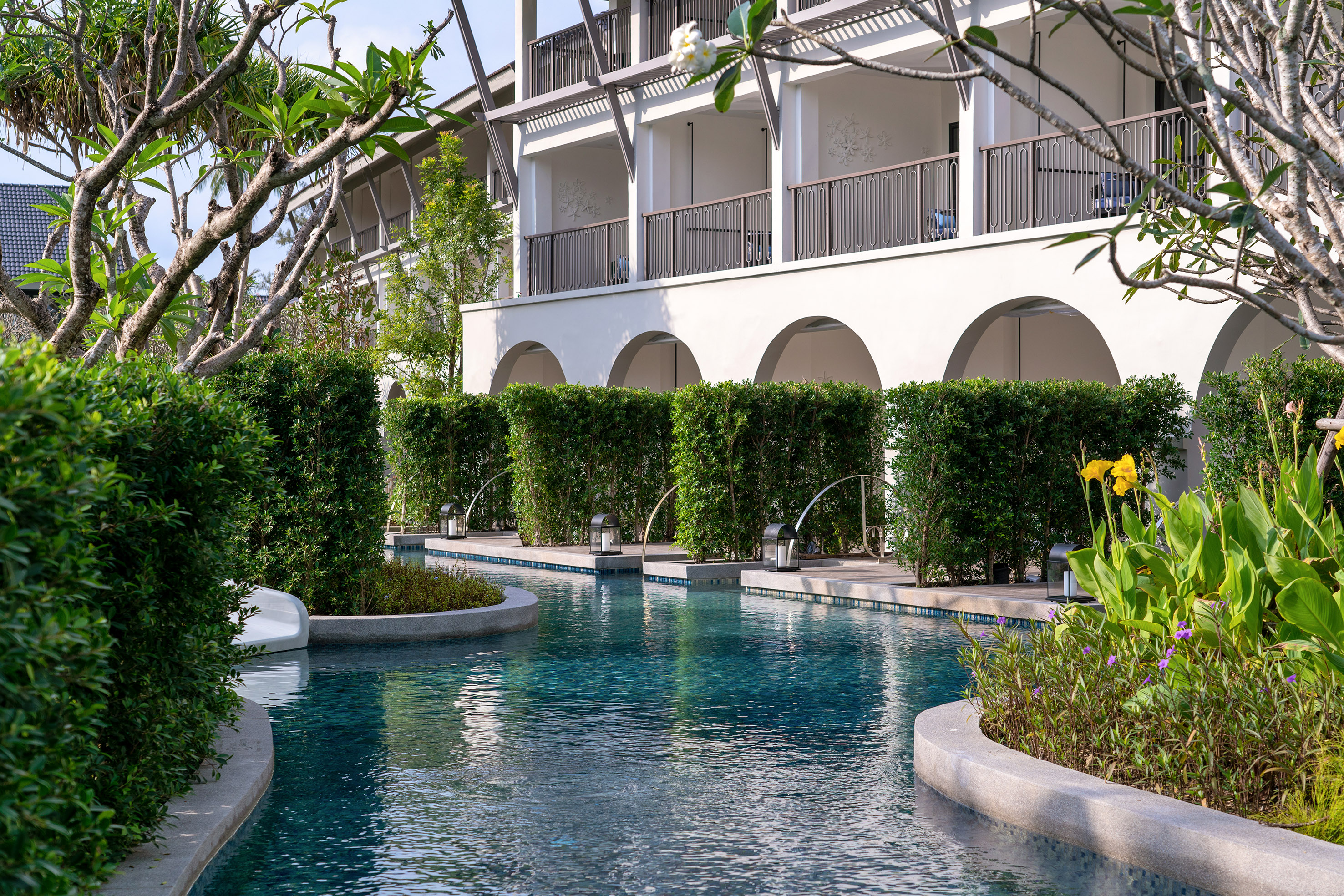 a pool with bushes and trees around it