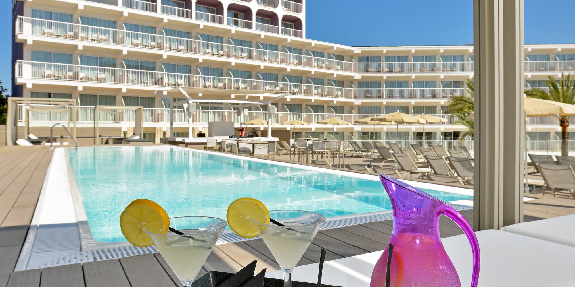 a tray of fruit and a pitcher on a table with a pool in the background