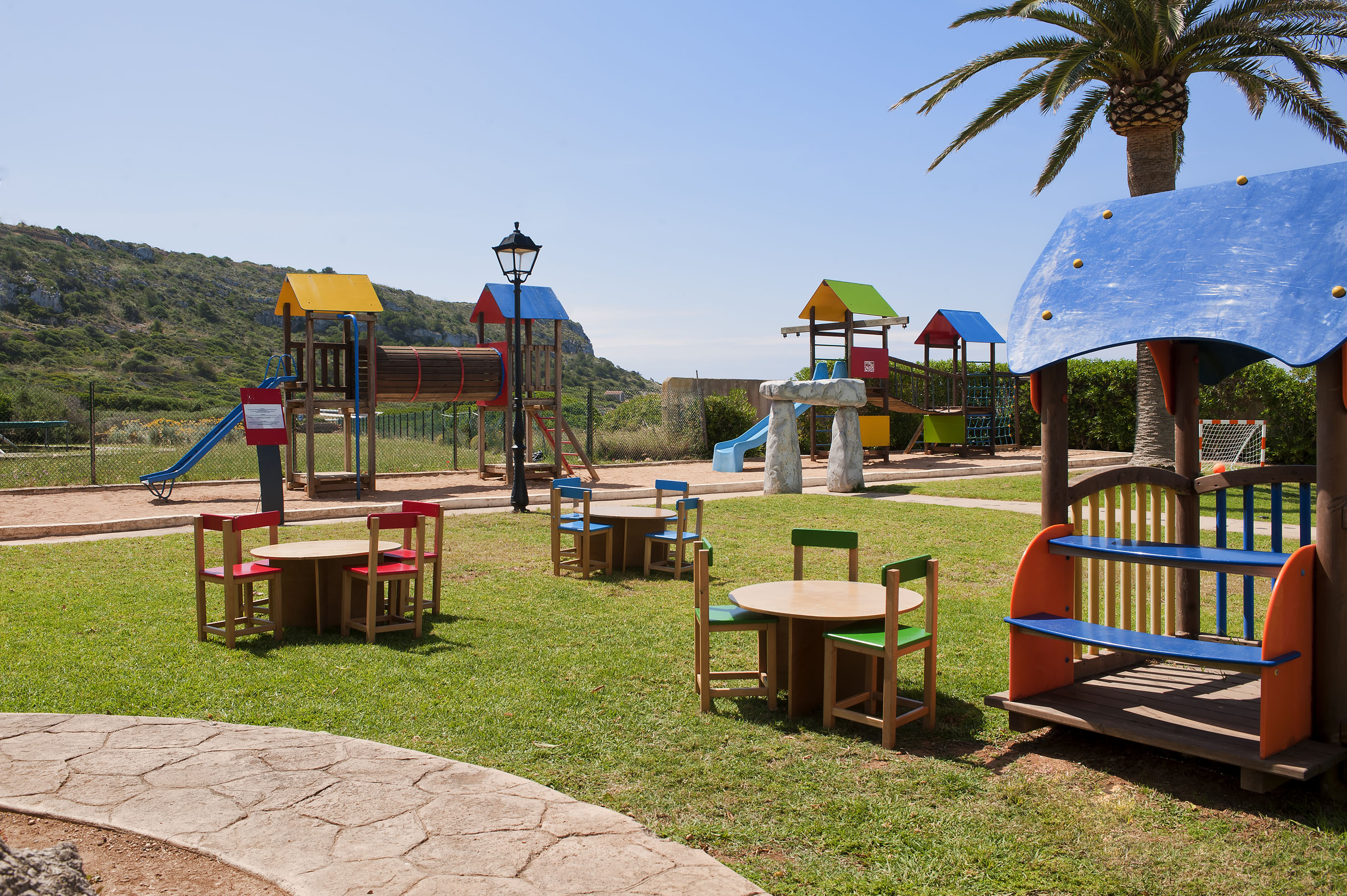 Resort kids' playground with slides, trampolines, picnic tables, and ocean.