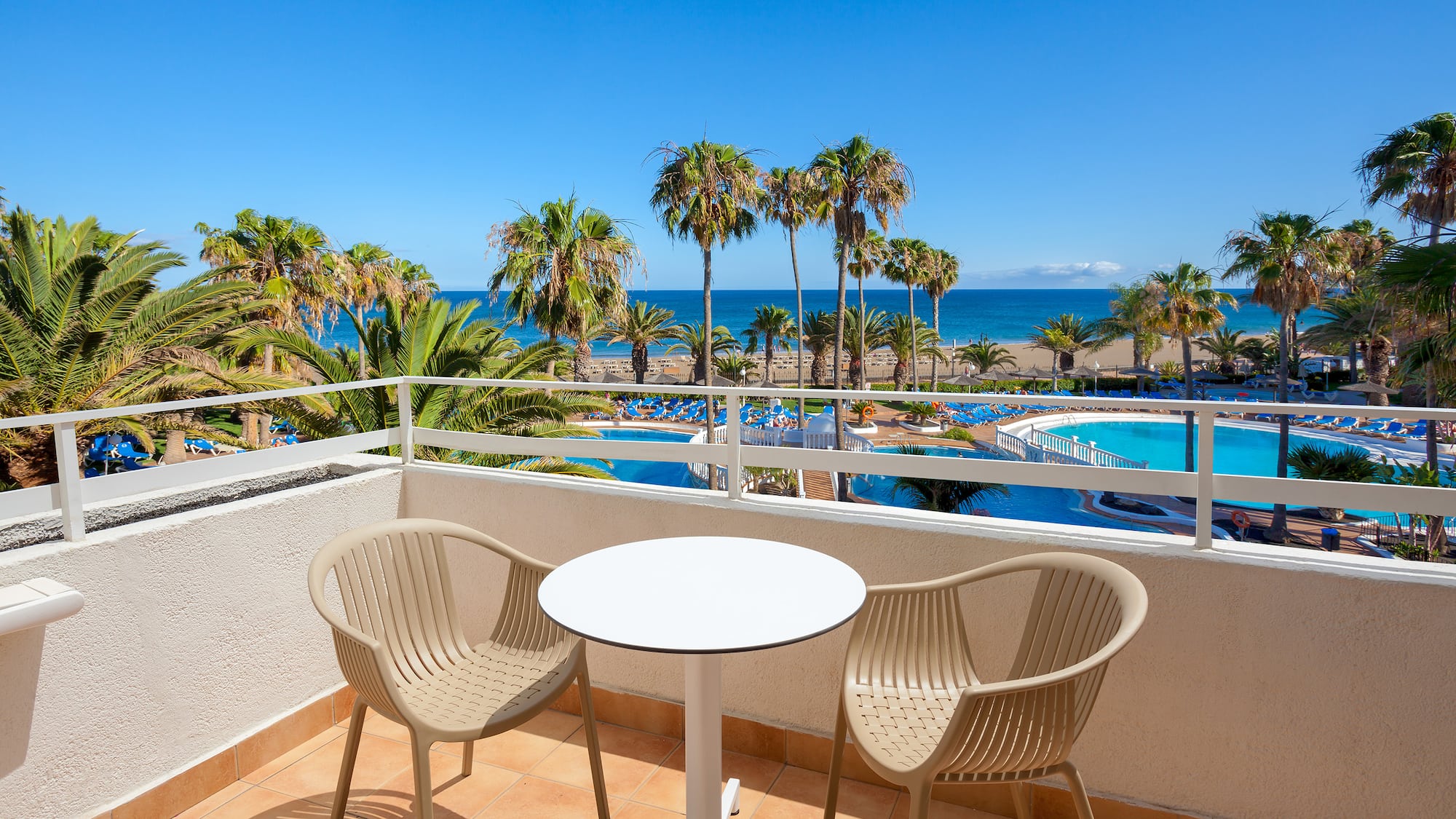 a table and chairs on a balcony overlooking a body of water