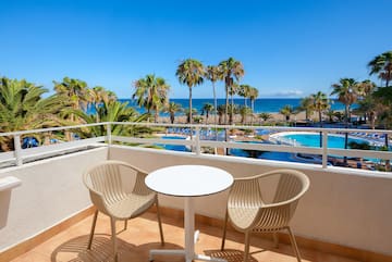 a table and chairs on a balcony overlooking a body of water