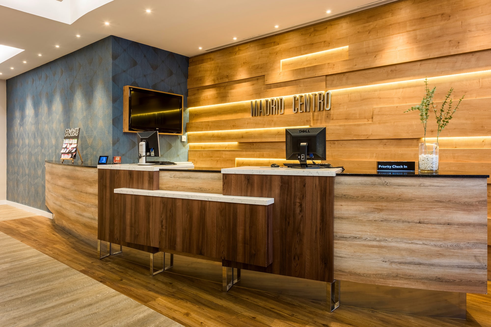 Modern Madrid Centro hotel reception with wood desk and illuminated sign.