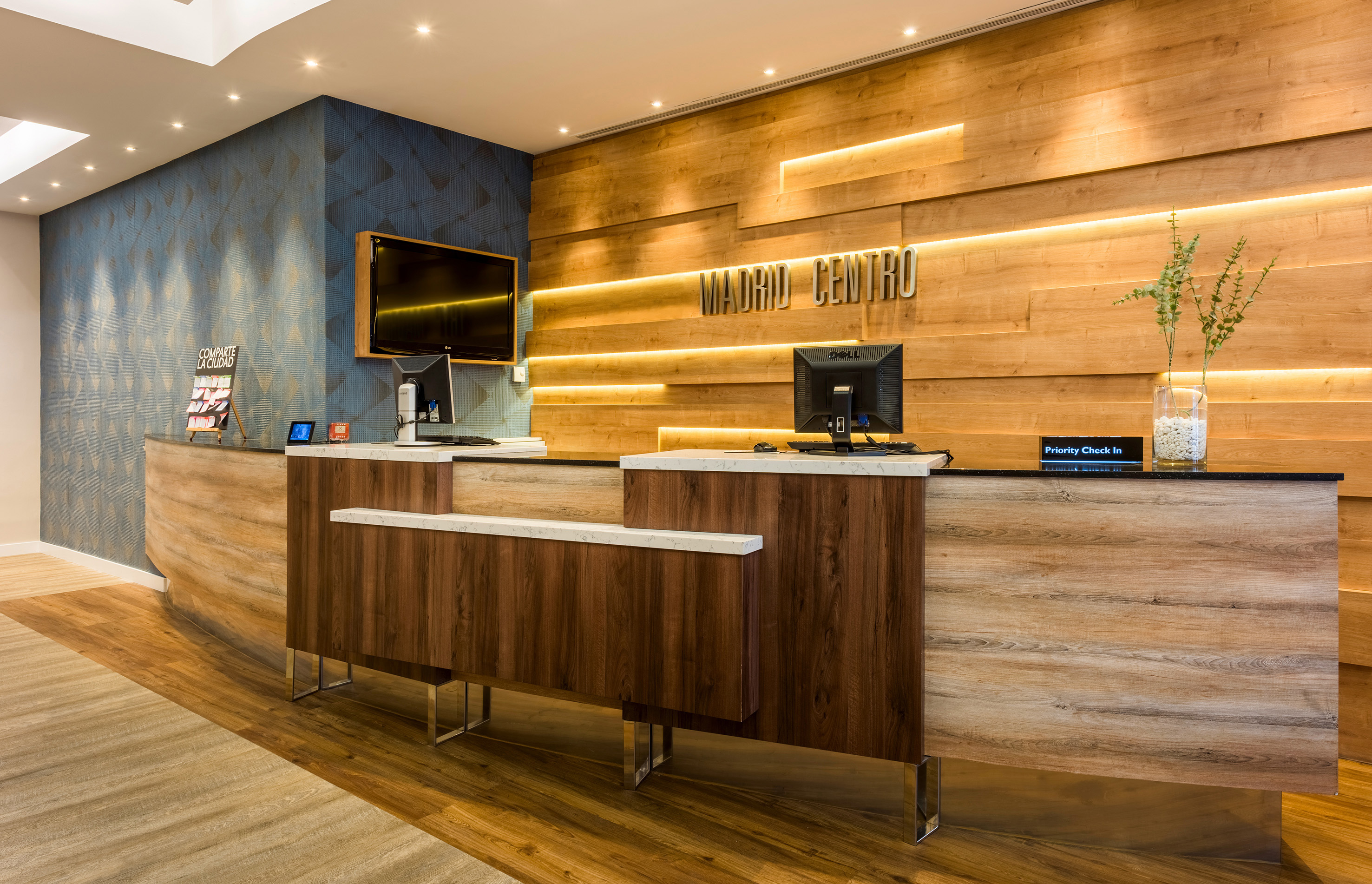 Modern Madrid Centro hotel reception with wood desk and illuminated sign.