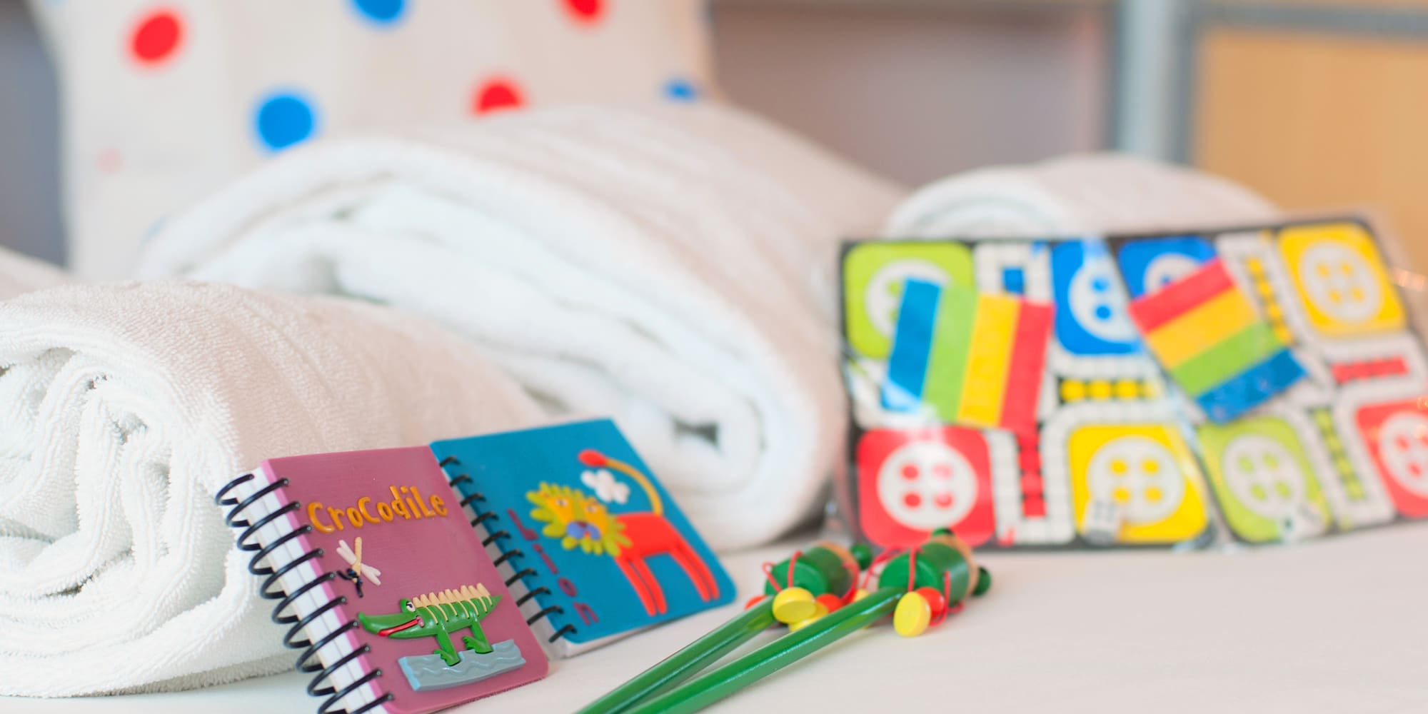 a group of notebooks and a pair of crayons on a bed