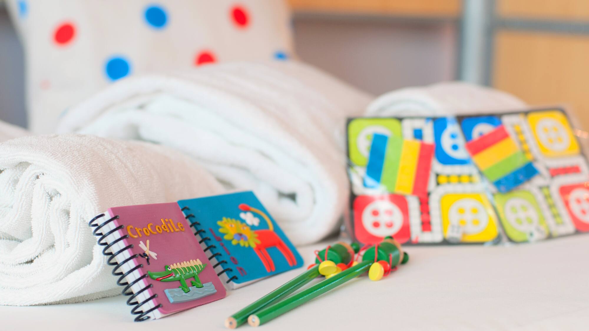 a group of notebooks and a pair of crayons on a bed