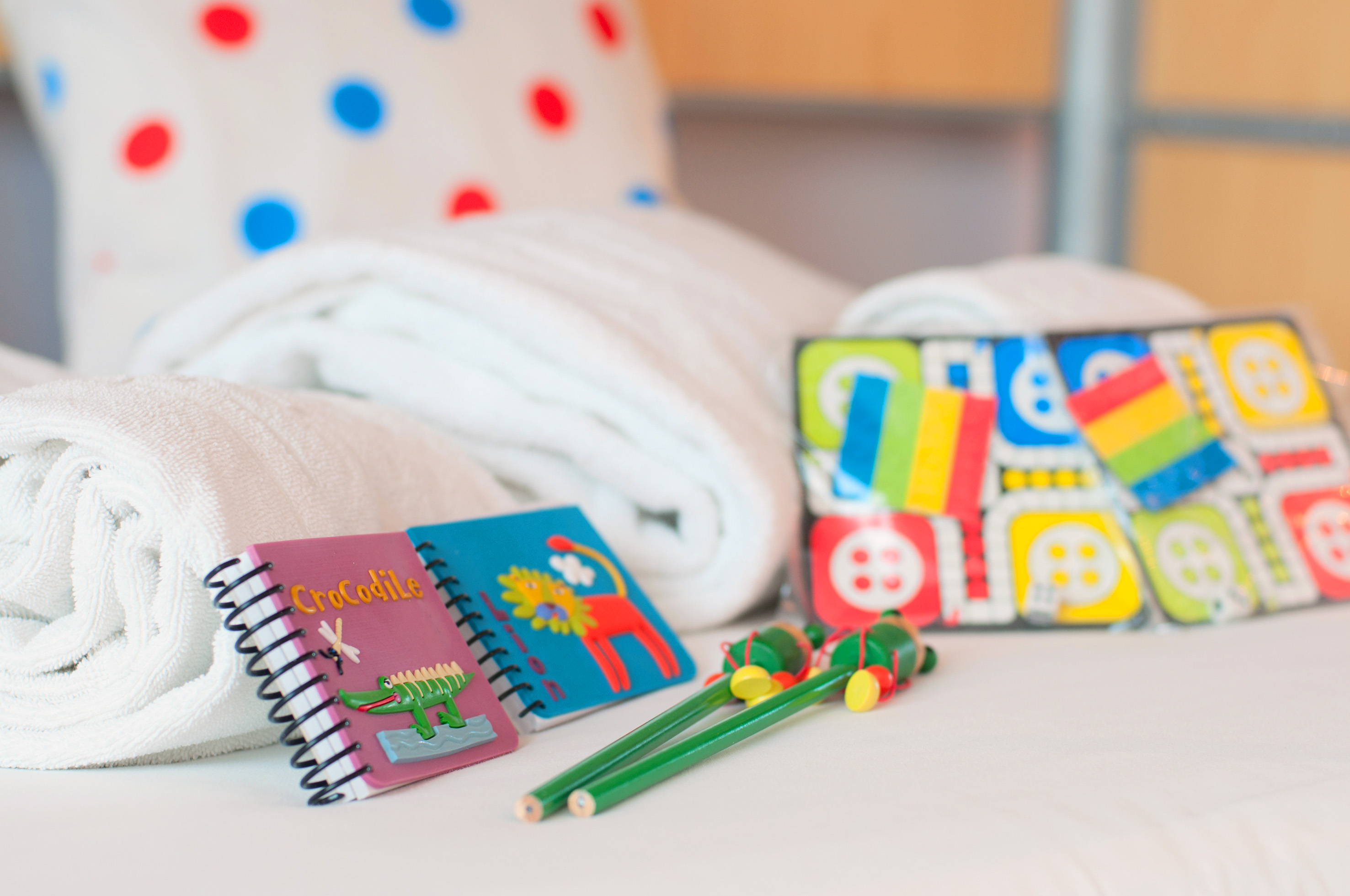 a group of notebooks and a pair of crayons on a bed