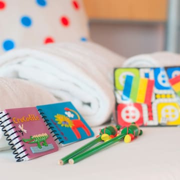 a group of notebooks and a pair of crayons on a bed