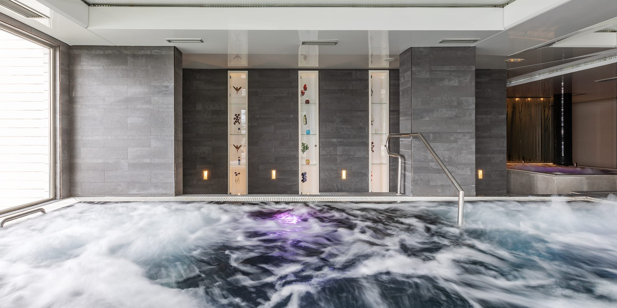a large indoor pool with water and a metal handrail