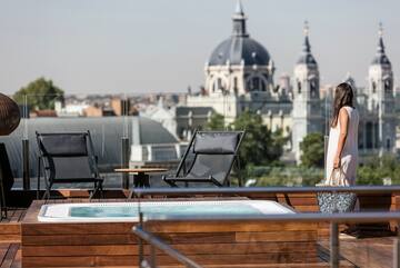 a woman standing on a deck with a hot tub and a city in the background
