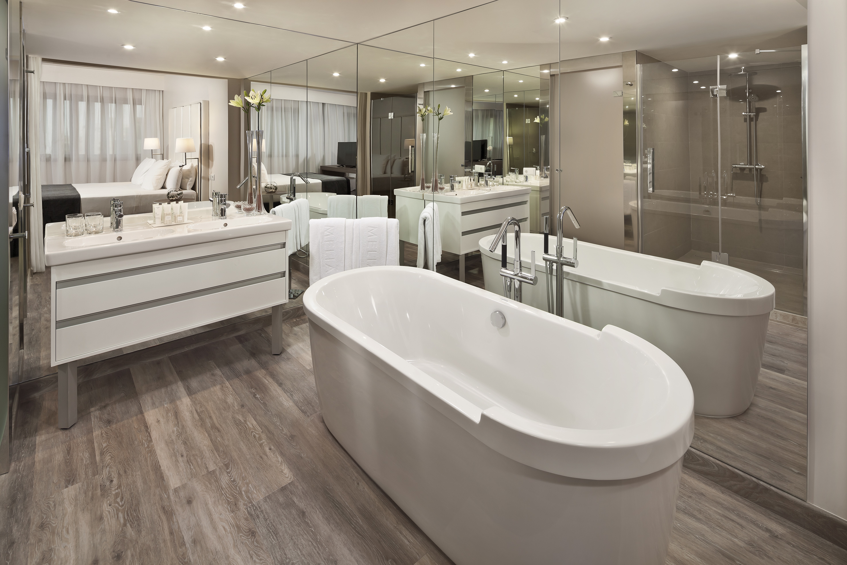 Hotel suite bathroom with freestanding tub, dual vanity, and glass shower.