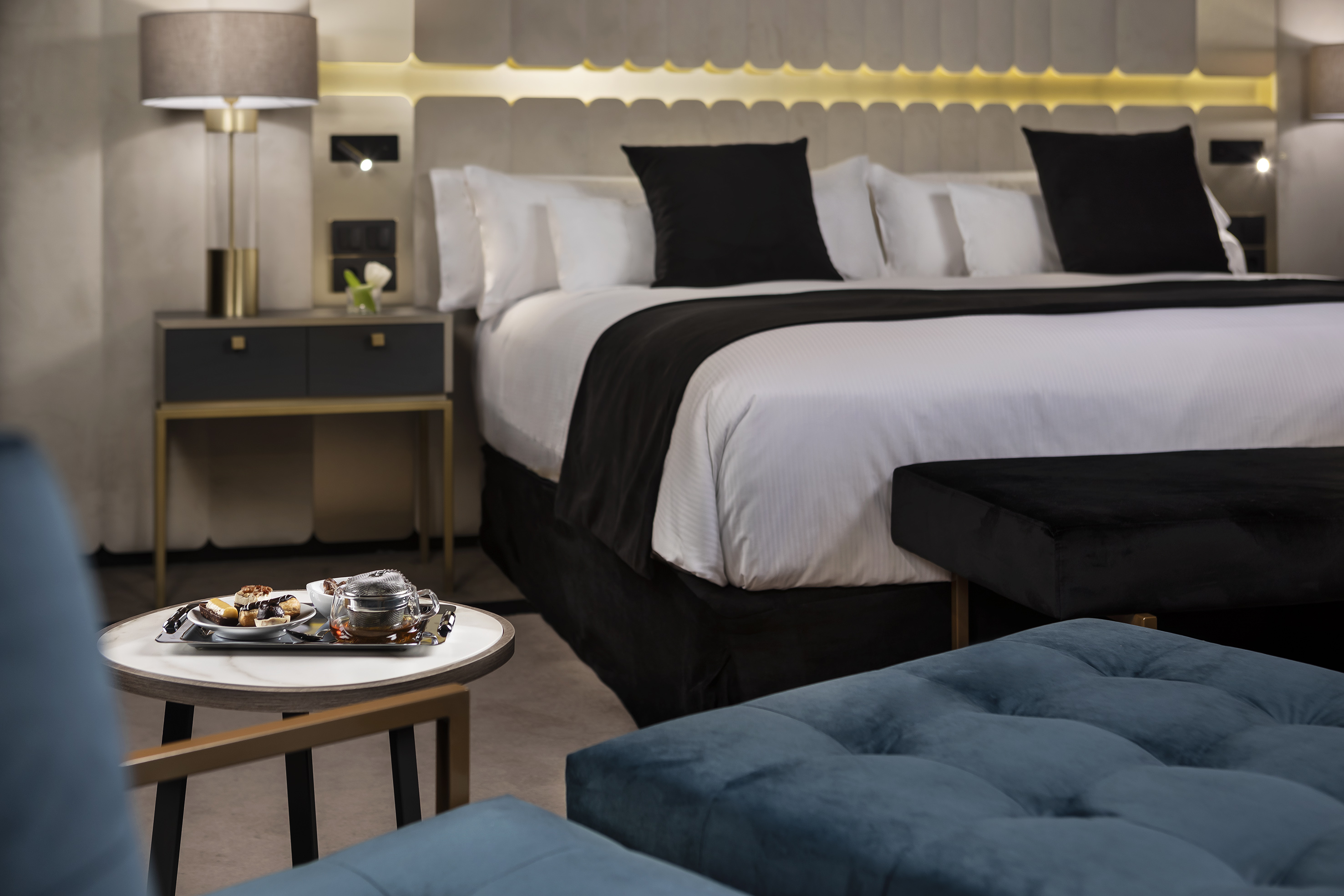 Elegant hotel room with plush king bed, stylish decor, and tea tray service.