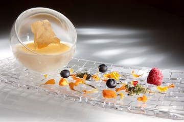 a glass bowl with a bowl of liquid and fruit on a glass plate