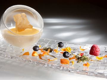 a glass bowl with a bowl of liquid and fruit on a glass plate