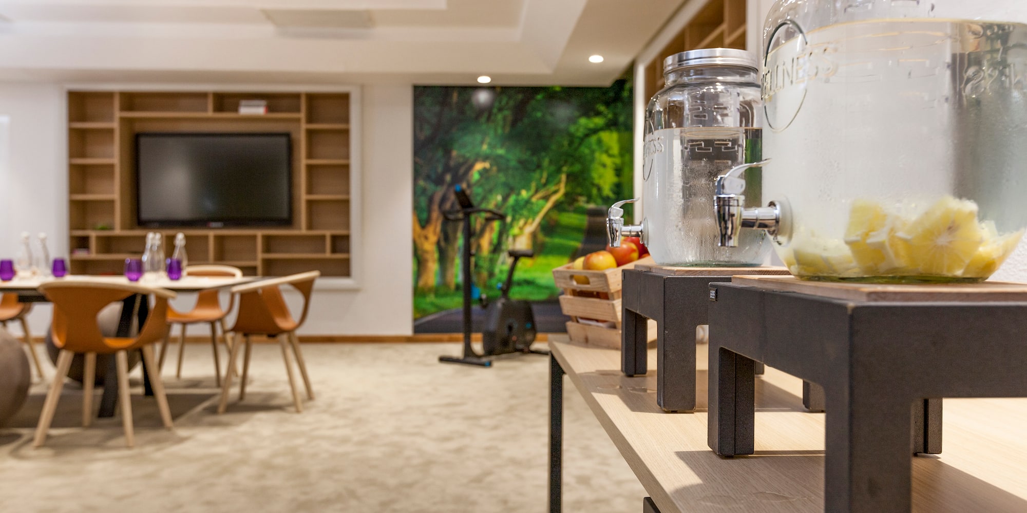 a room with a table and chairs and a large table with a tv and a couple of glass jars with water