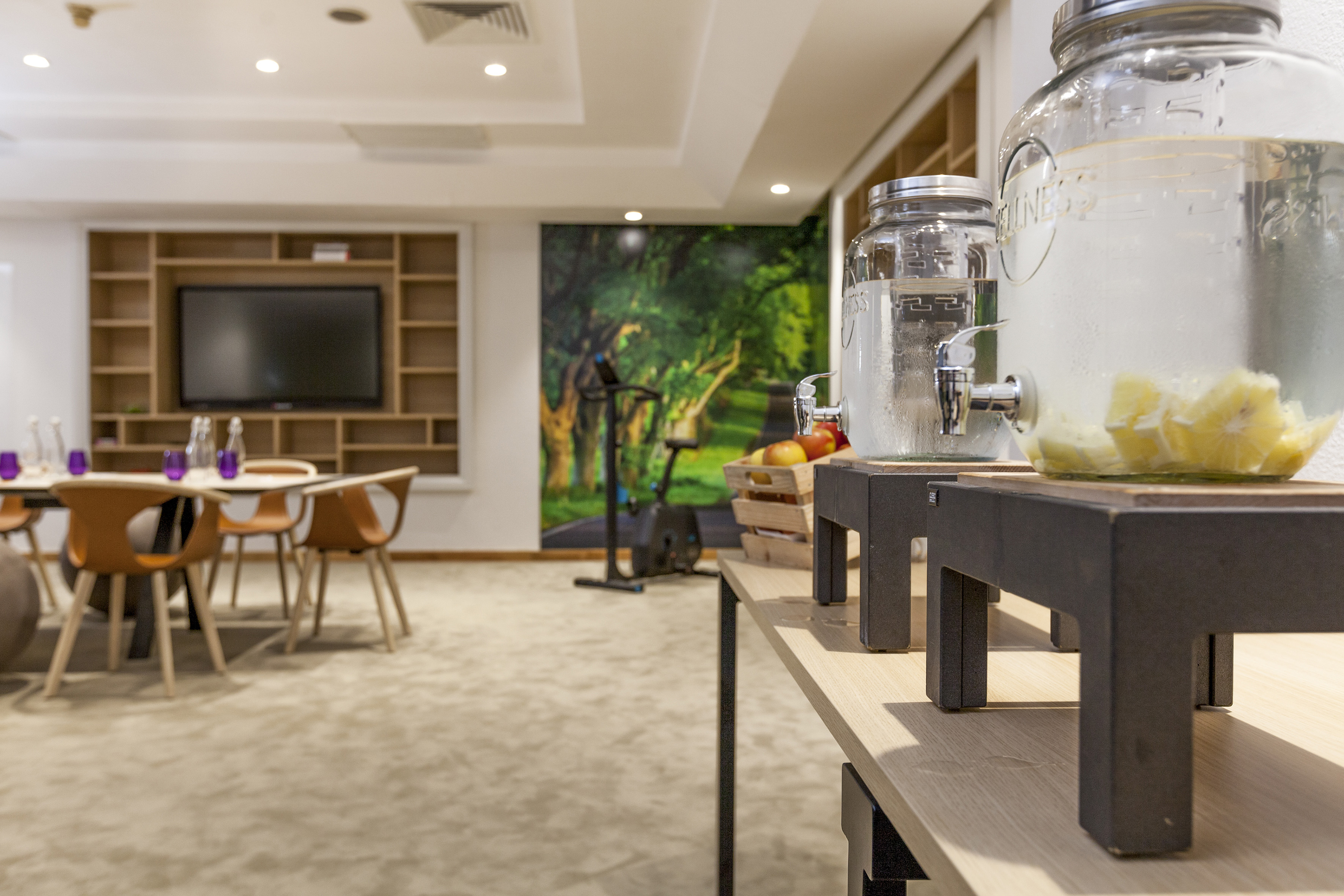 a room with a table and chairs and a large table with a tv and a couple of glass jars with water