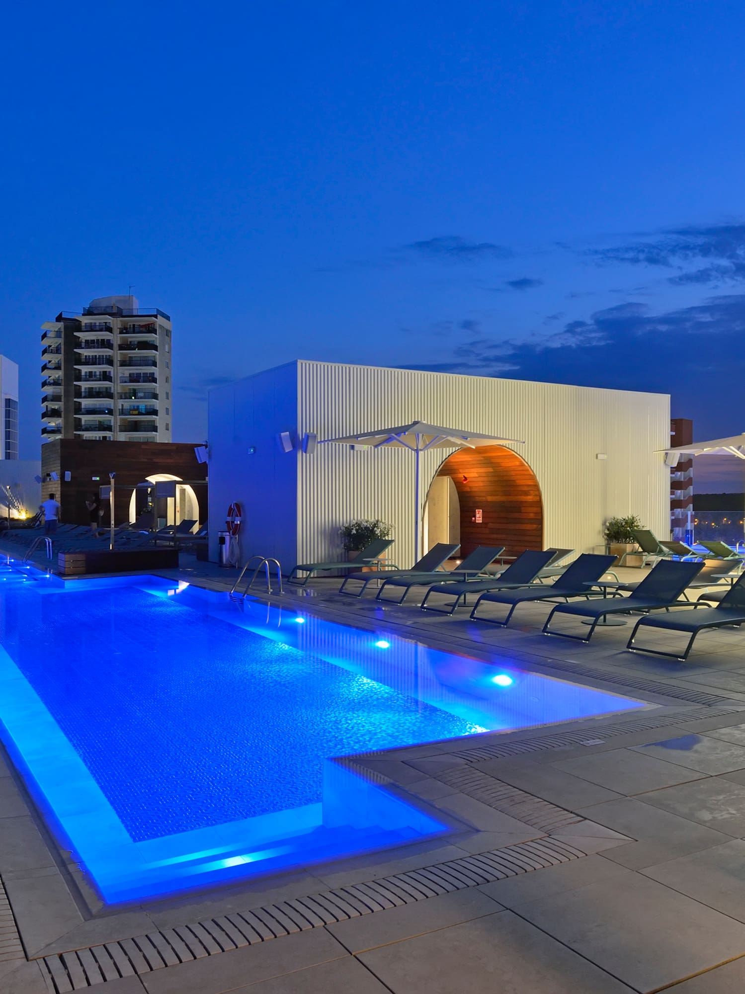 a pool with lounge chairs and a building in the background