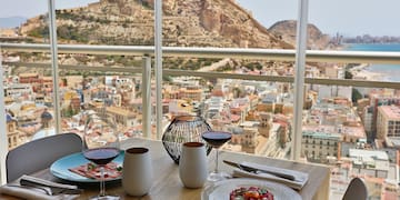 a table with plates of food and glasses on it with a view of a city