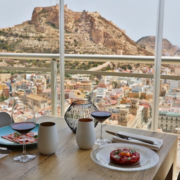a table with plates of food and glasses on it with a view of a city