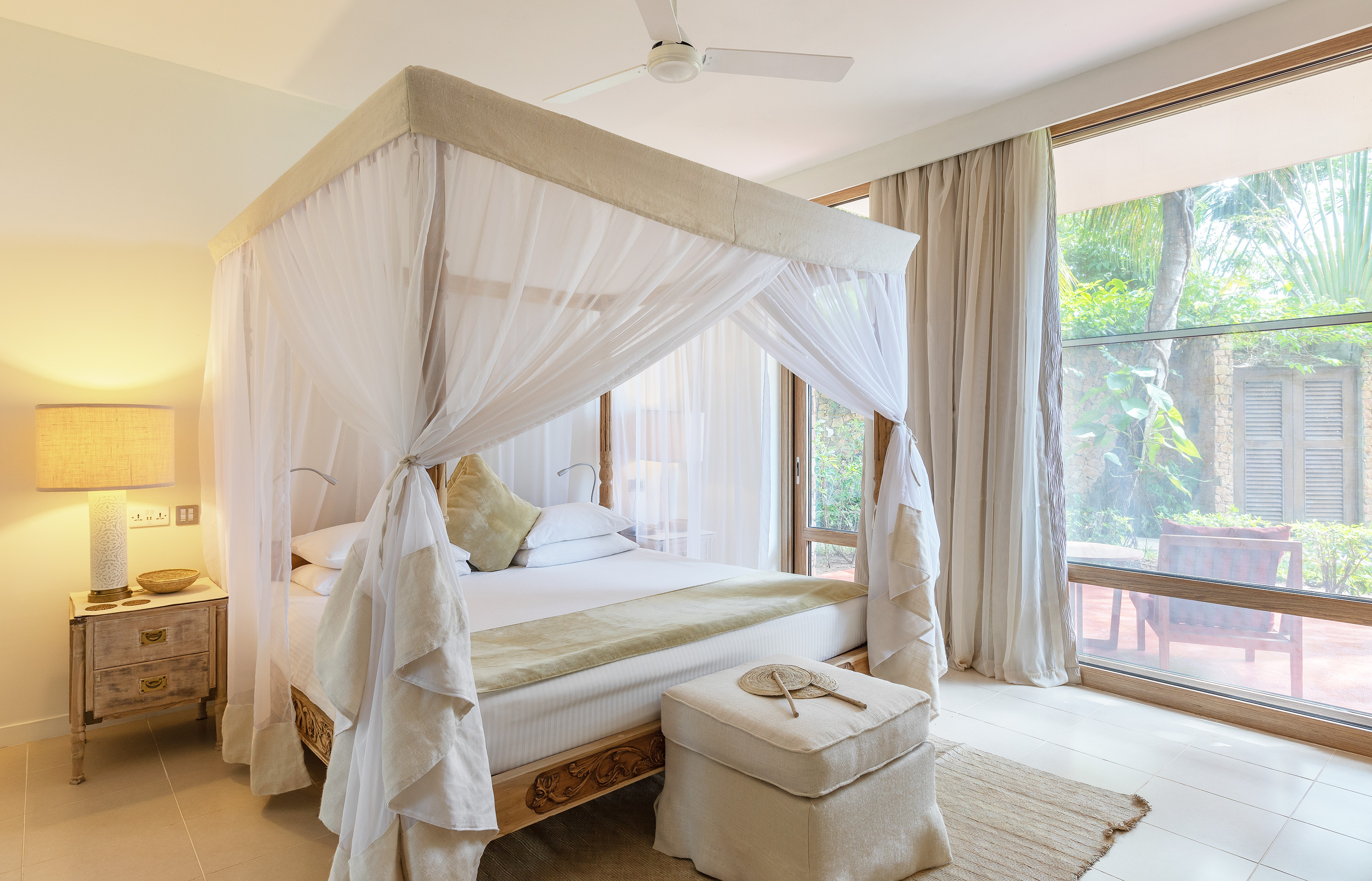 Luxury bedroom with canopy bed and tropical garden view.