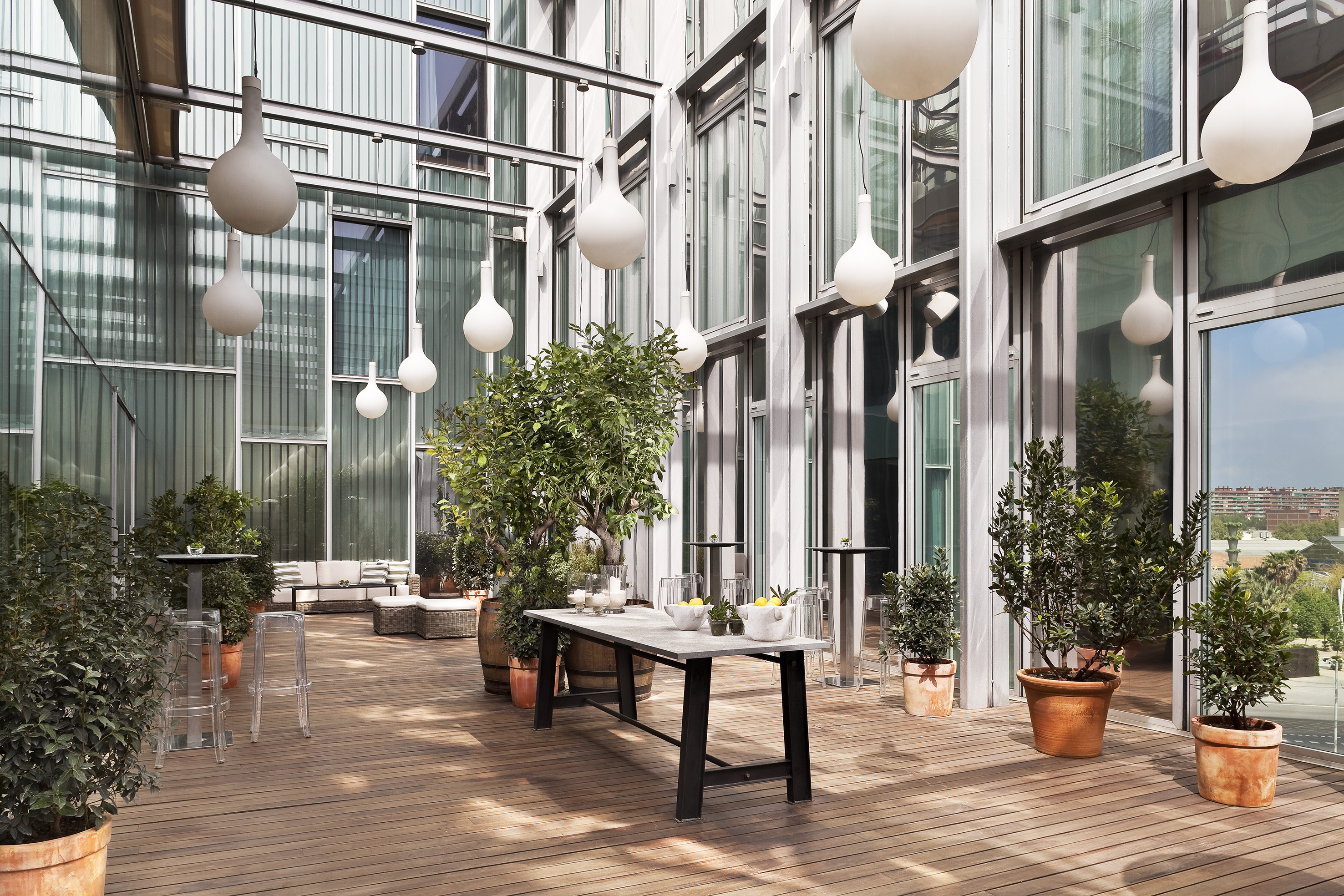 Modern outdoor terrace with wooden deck, potted plants, and contemporary lighting.