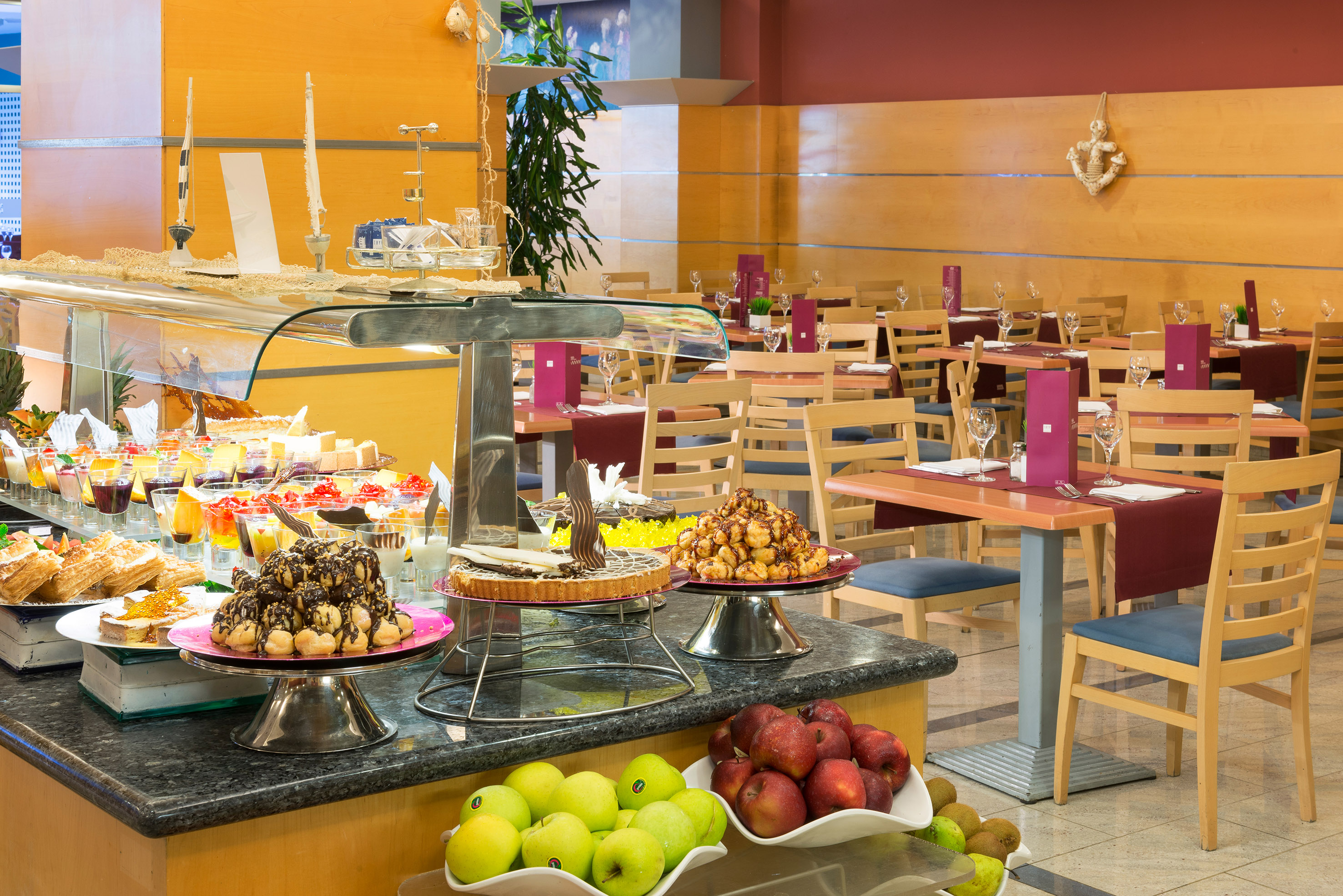 Colorful dessert and fresh fruit buffet in a hotel restaurant dining area.