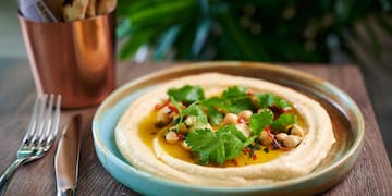 a plate of hummus with greens on it