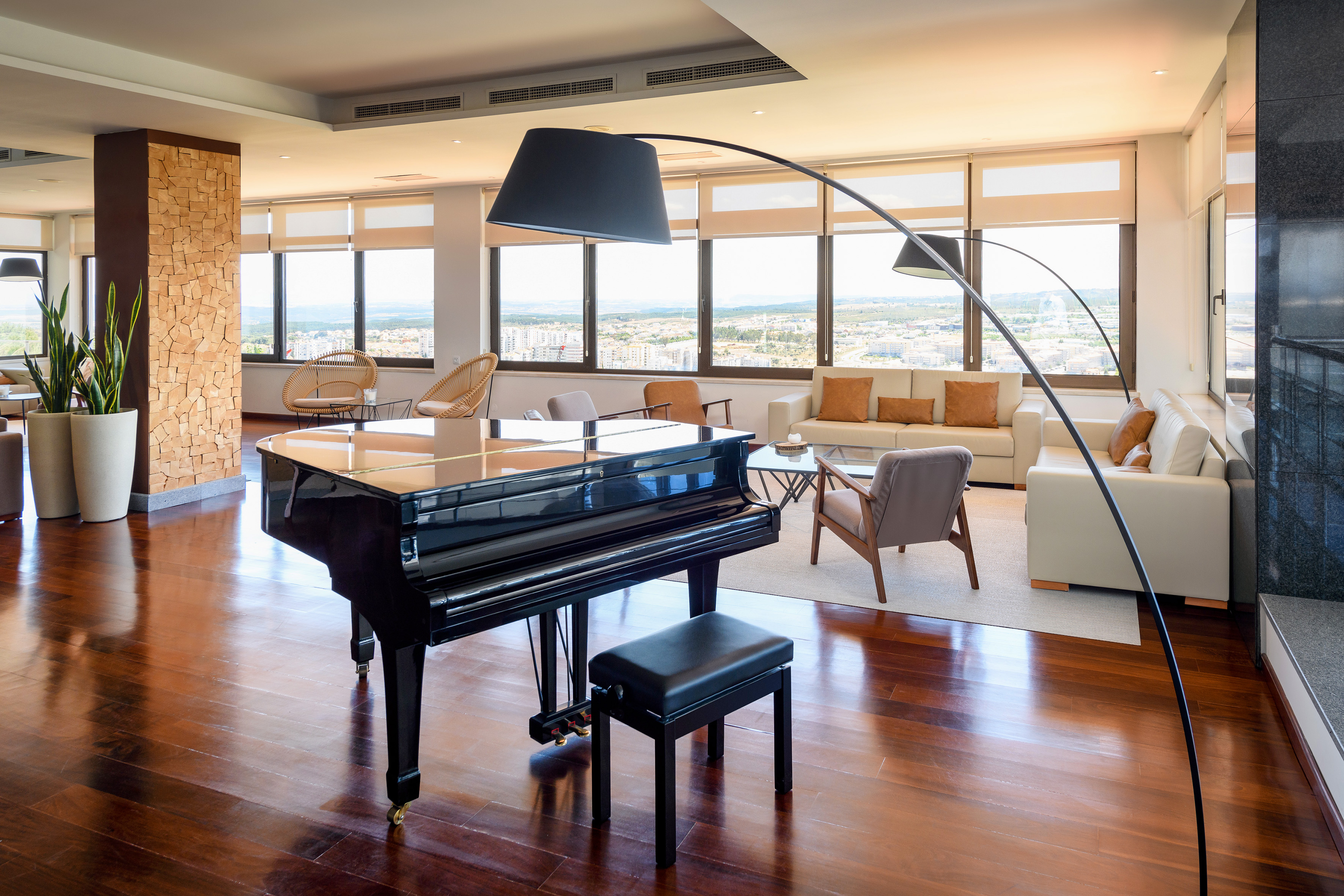 Spacious modern lounge with black grand piano, city view, and hardwood floors.