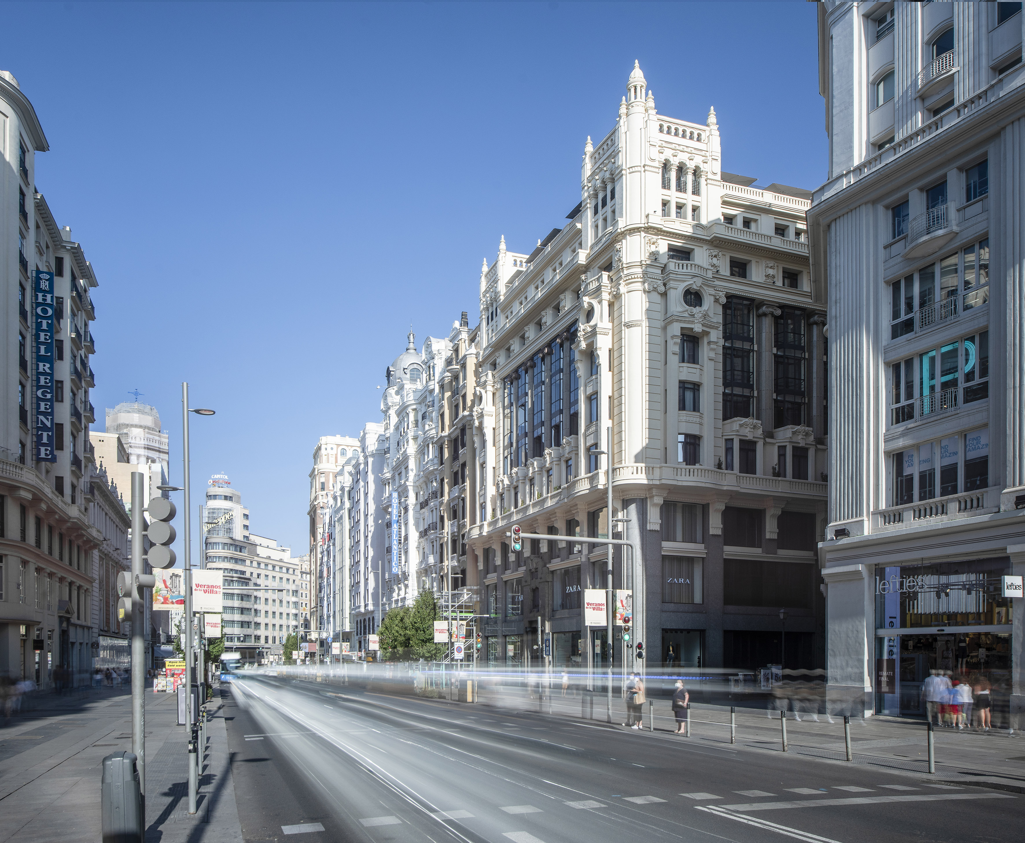Gran Vía, Madrid: elegant architecture, clear sky, and streaks of city traffic.