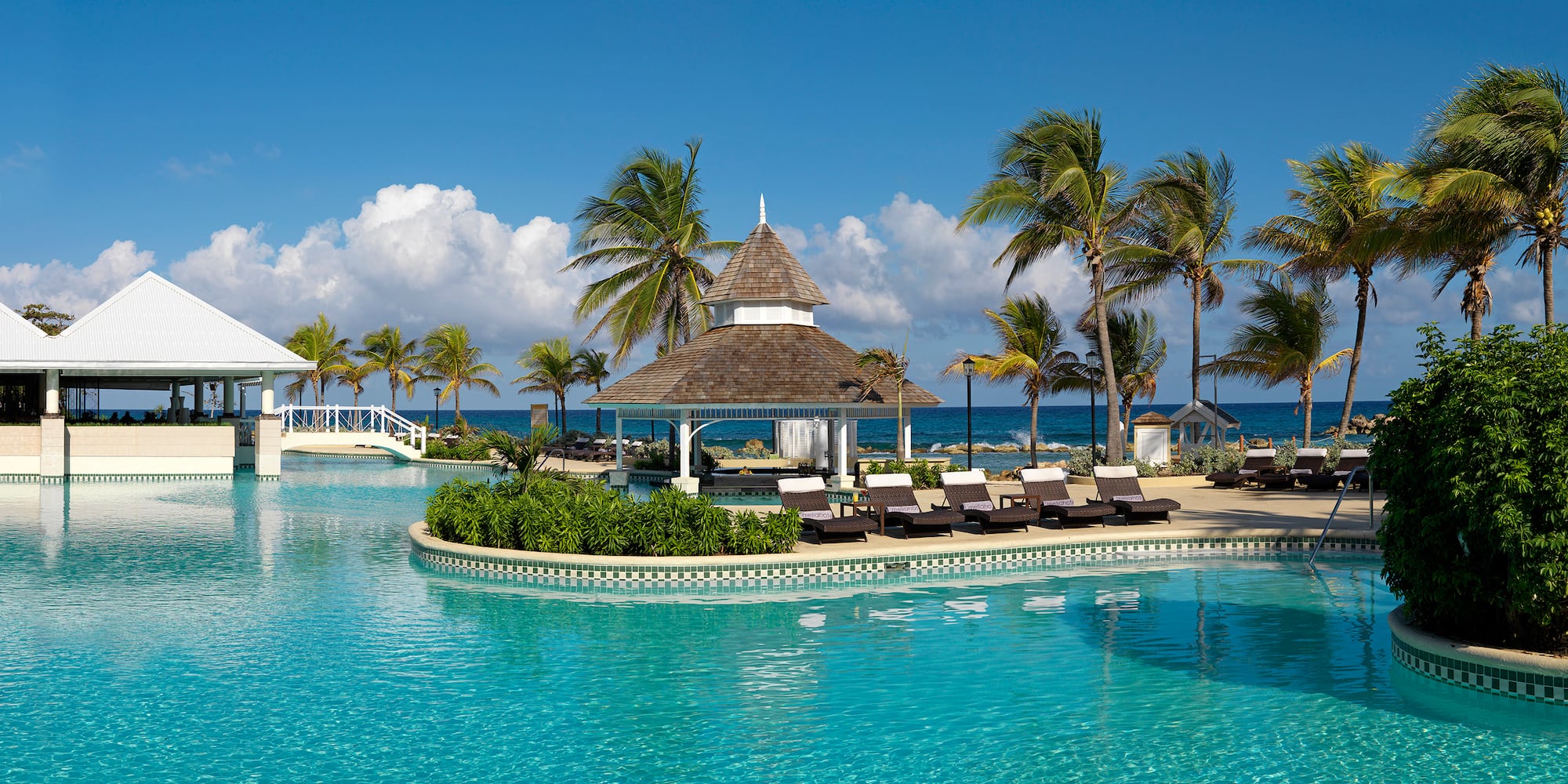 a pool with a gazebo and palm trees