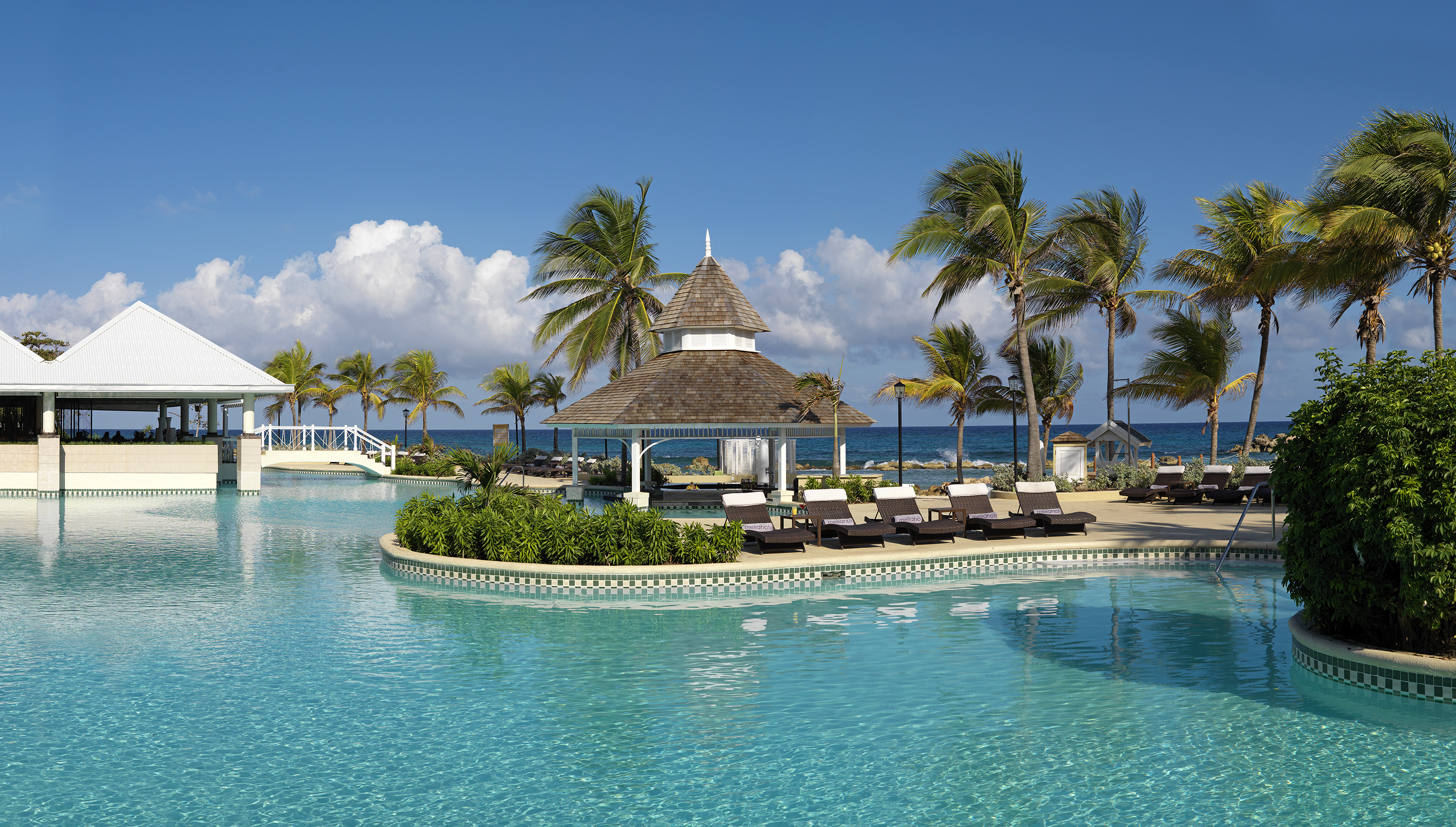 a pool with a gazebo and palm trees