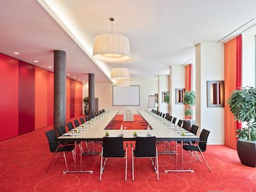 a long conference room with red carpet and white walls