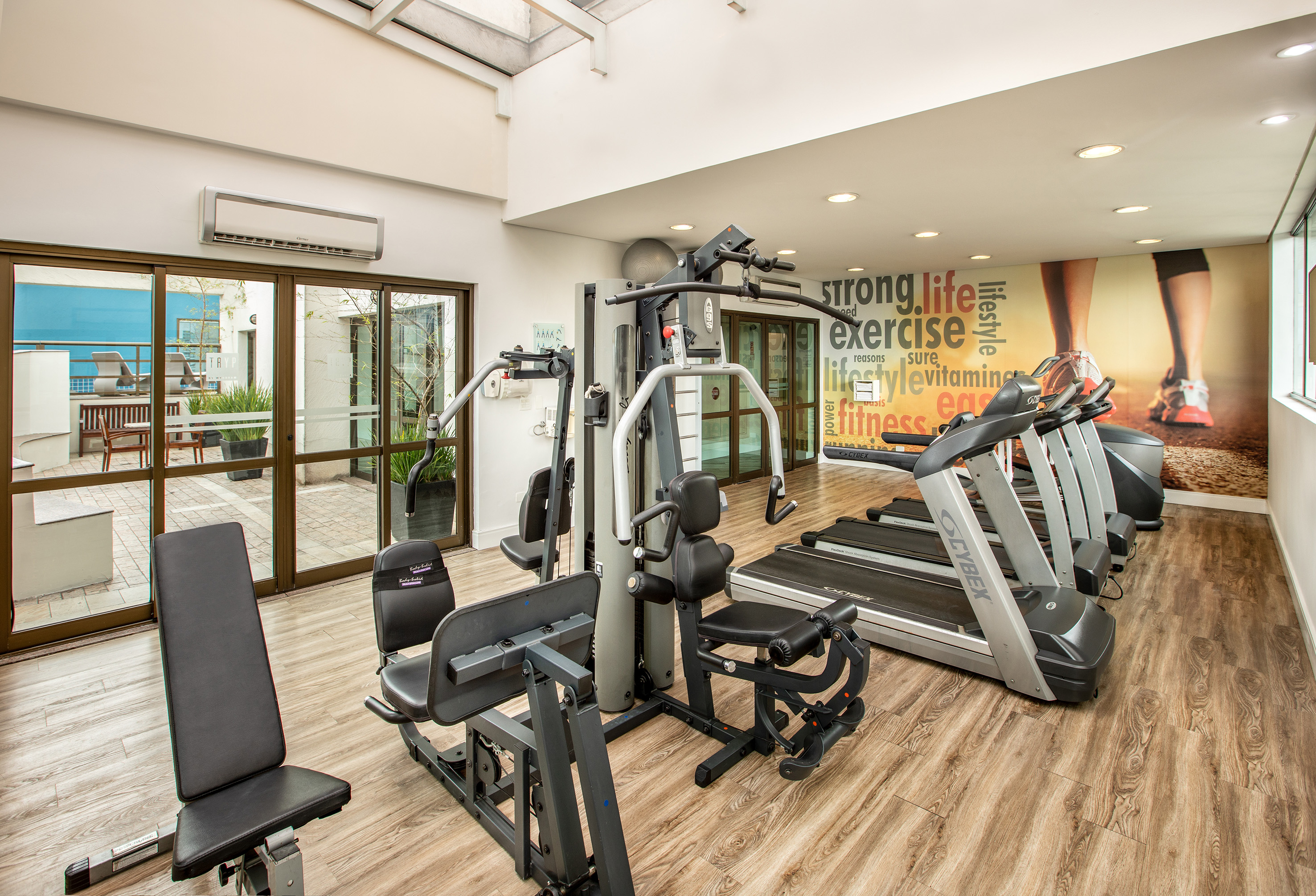 Bright gym with multiple treadmills, strength machines, and a vibrant fitness mural.
