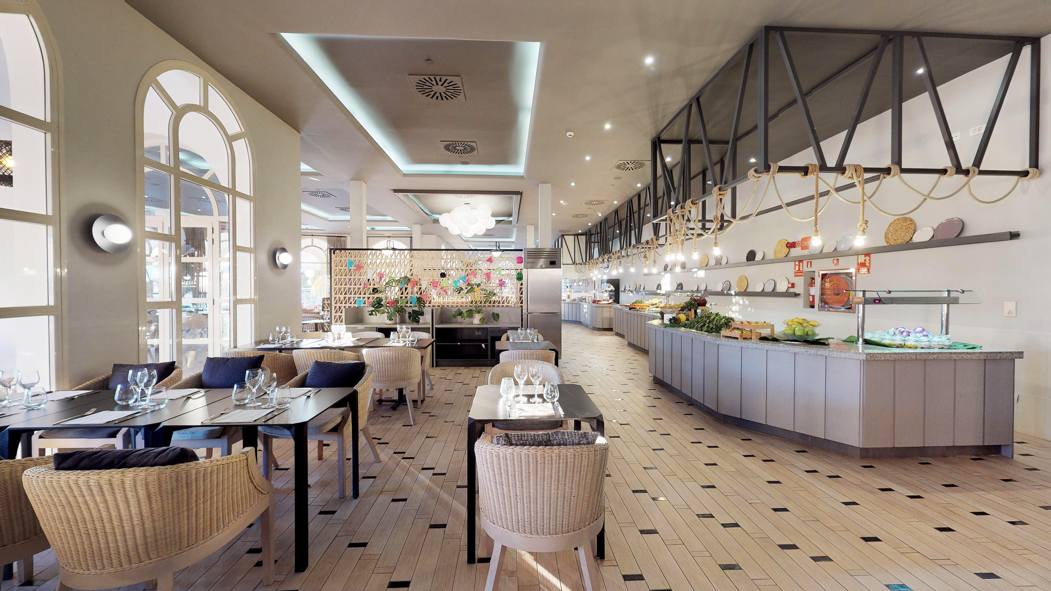 Spacious modern hotel restaurant with buffet food stations and dining tables.