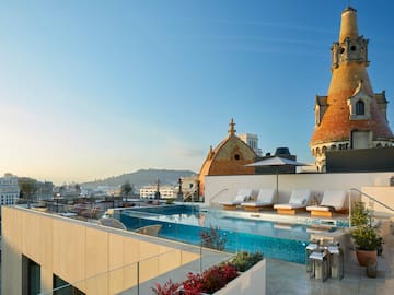 a pool with lounge chairs and a rooftop with a city in the background