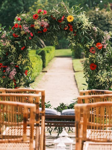 a flower arch with chairs in the background