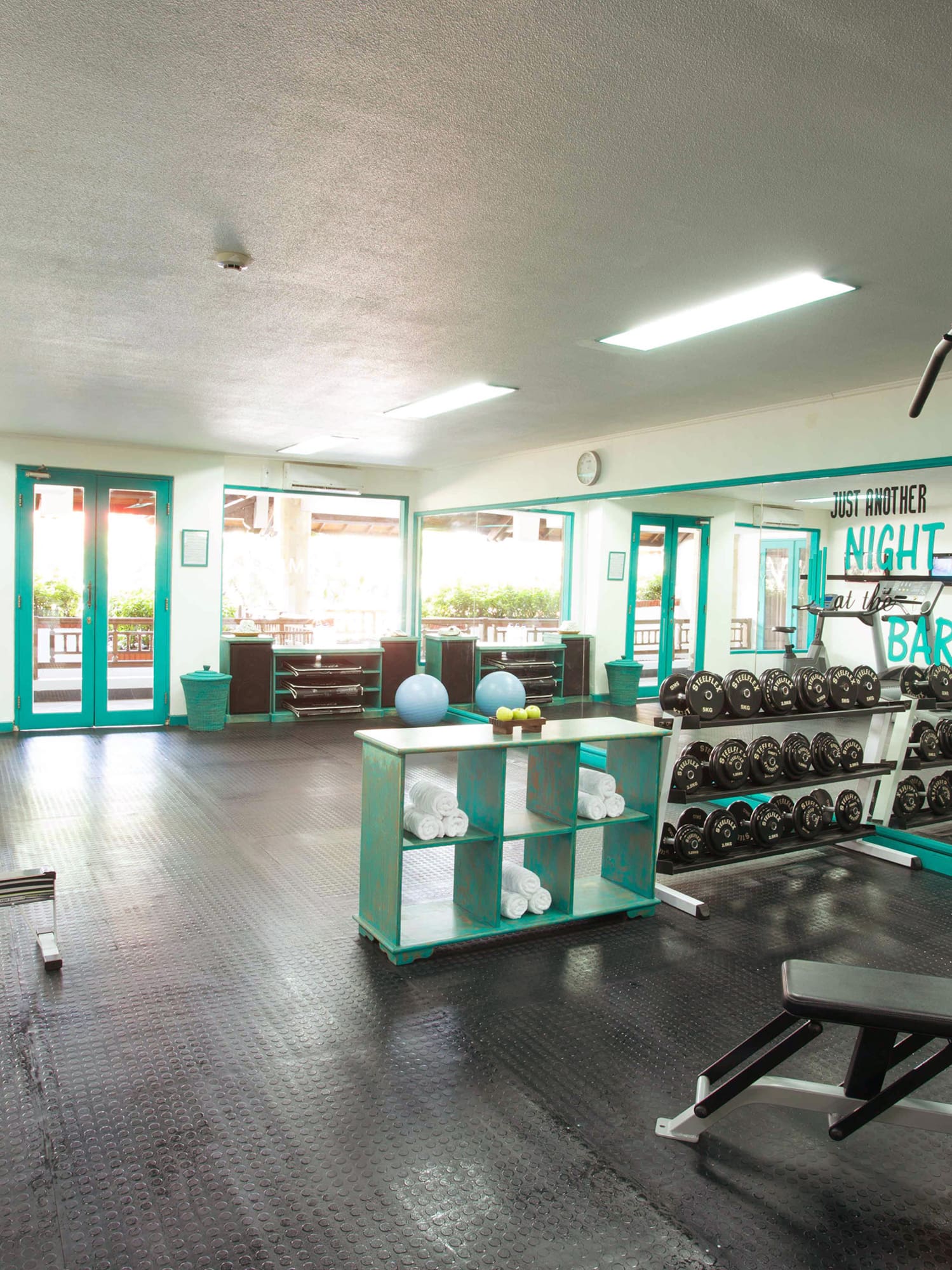 a room with exercise equipment and a shelf with weights