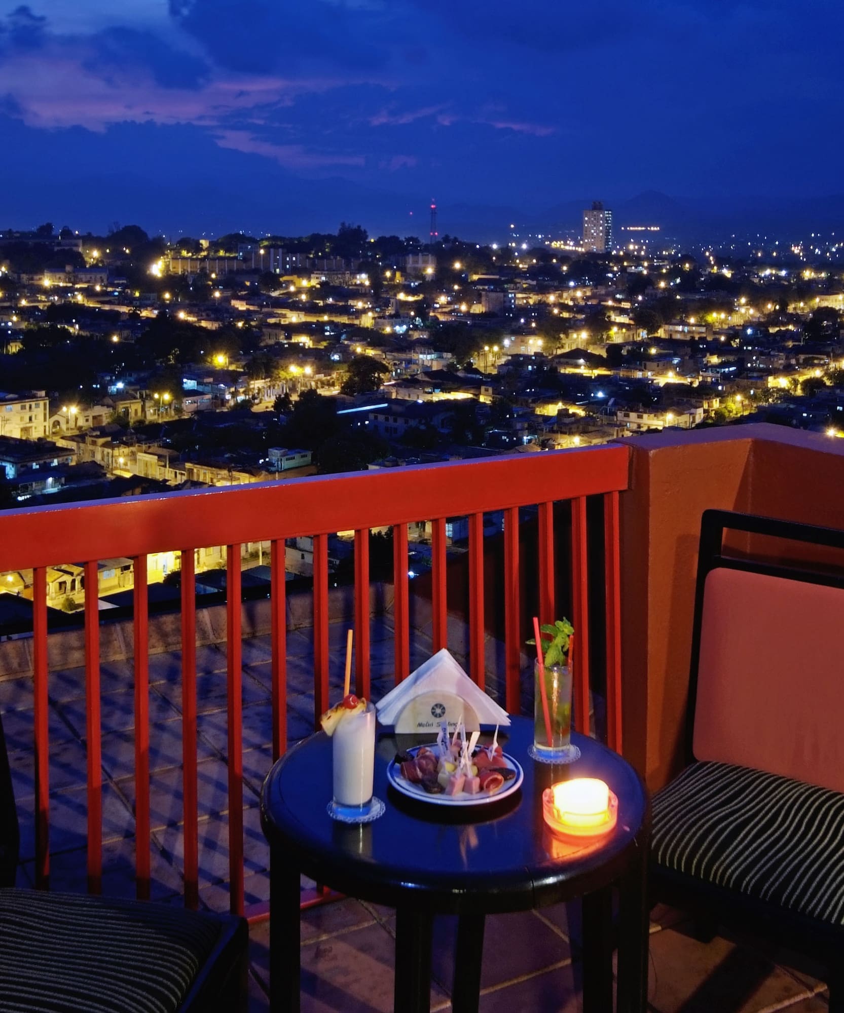 a table and chairs on a balcony overlooking a city