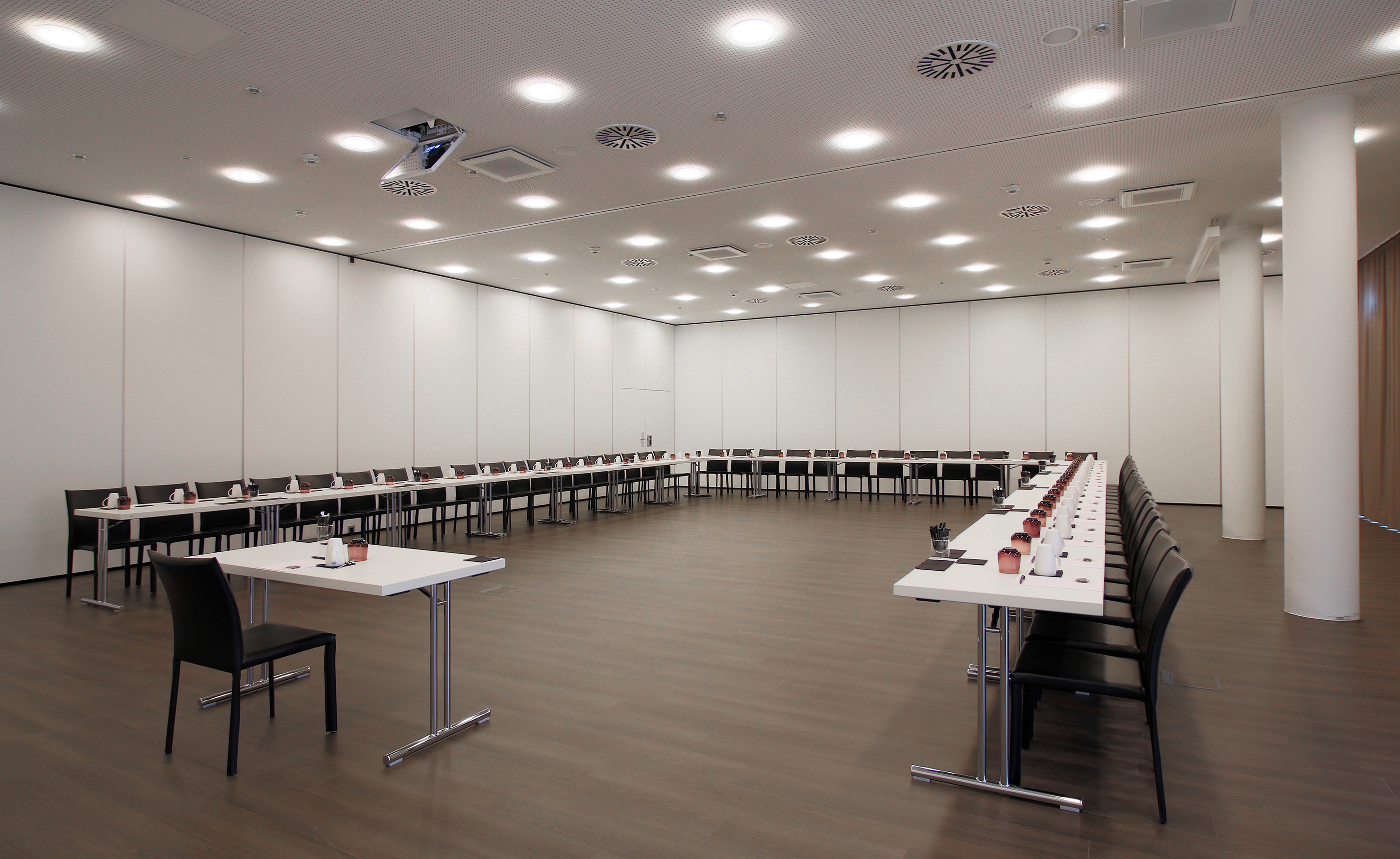 Modern U-shaped conference room setup with tables, chairs, and projector.