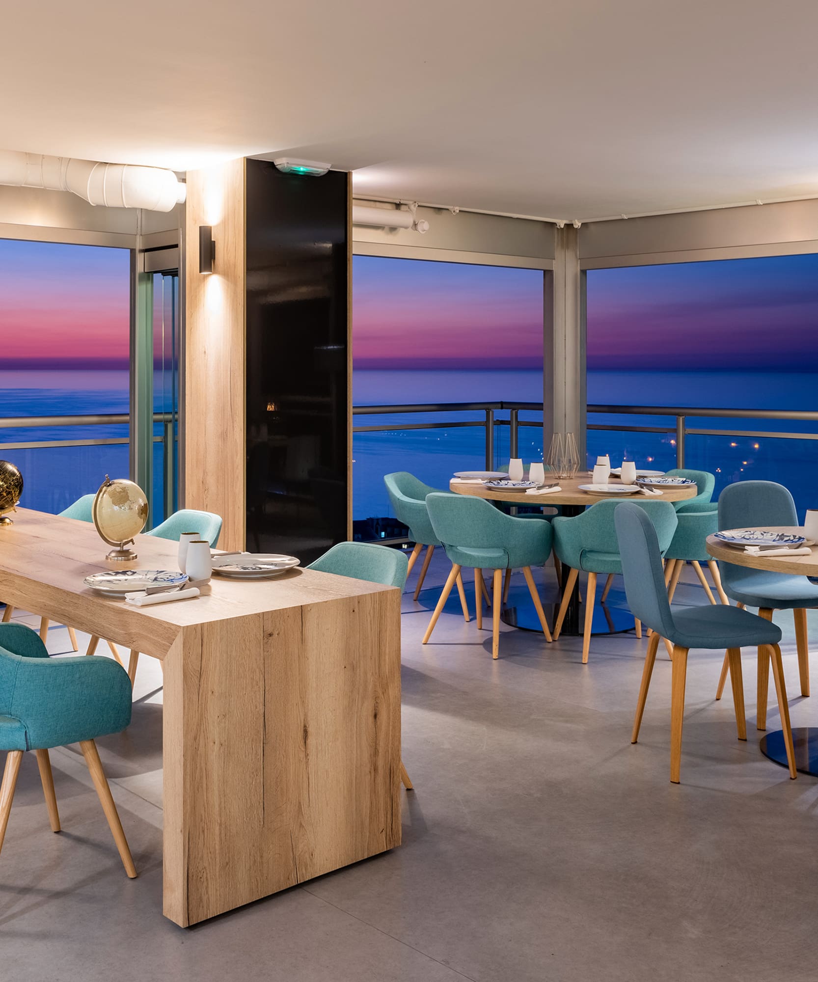 a room with a table and chairs and a balcony overlooking the ocean