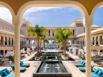 a pool with a fountain and chairs in front of a building