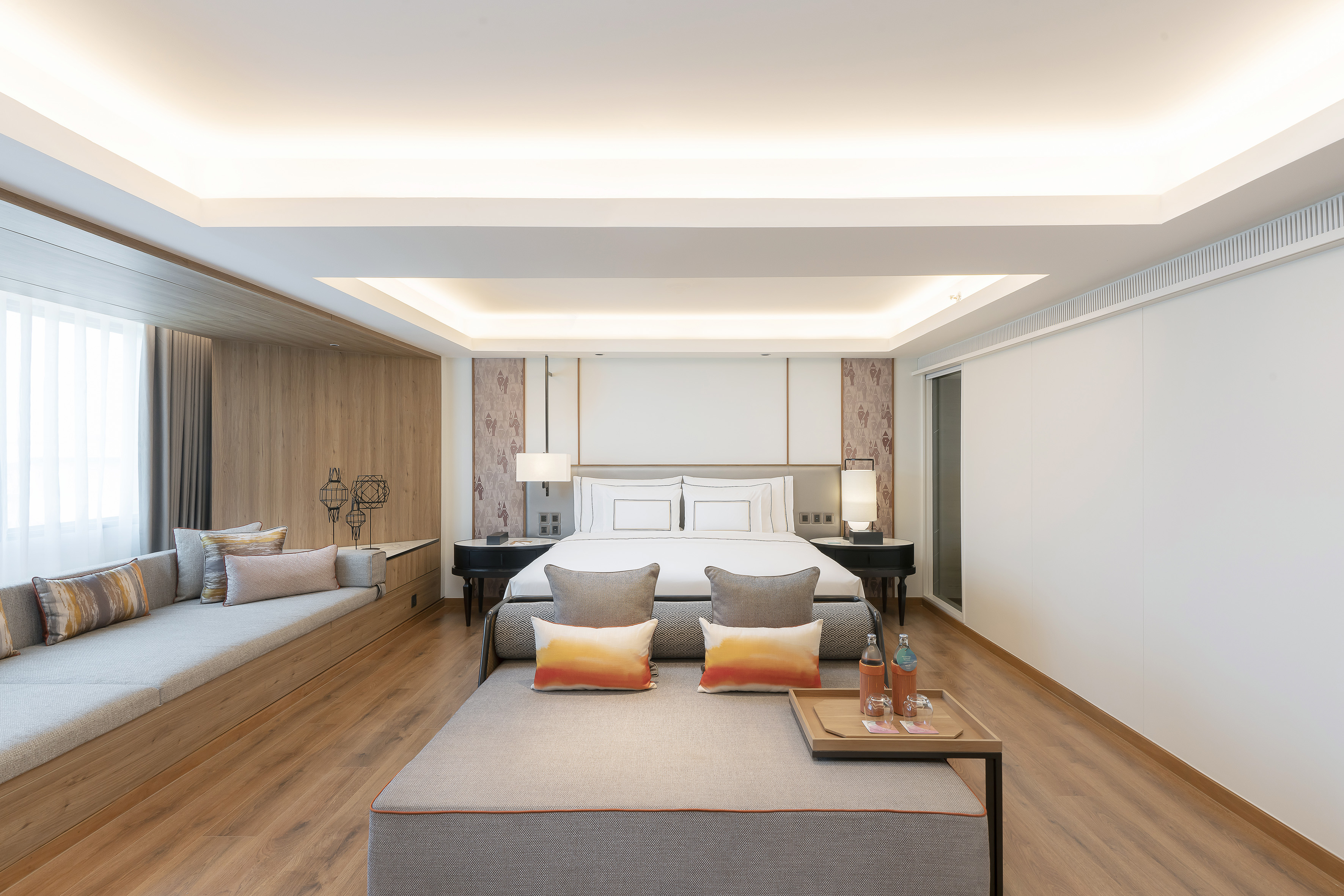 Contemporary hotel suite with king bed, built-in lounge, and wood paneling.