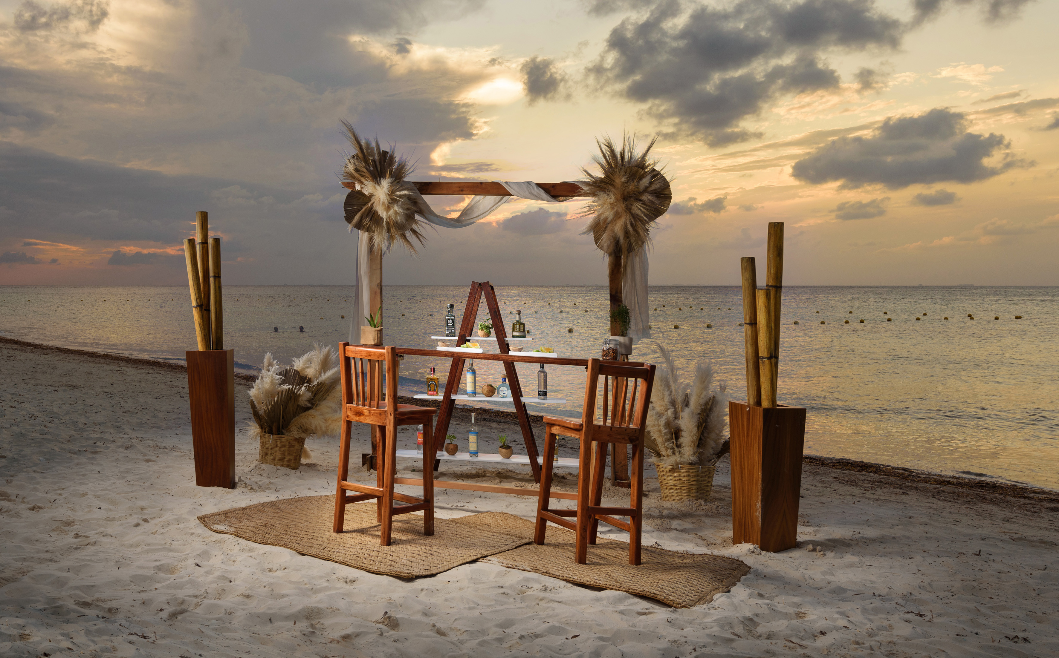 Sunset beach bar with decorated arch, stools, drinks on sand, ocean background.