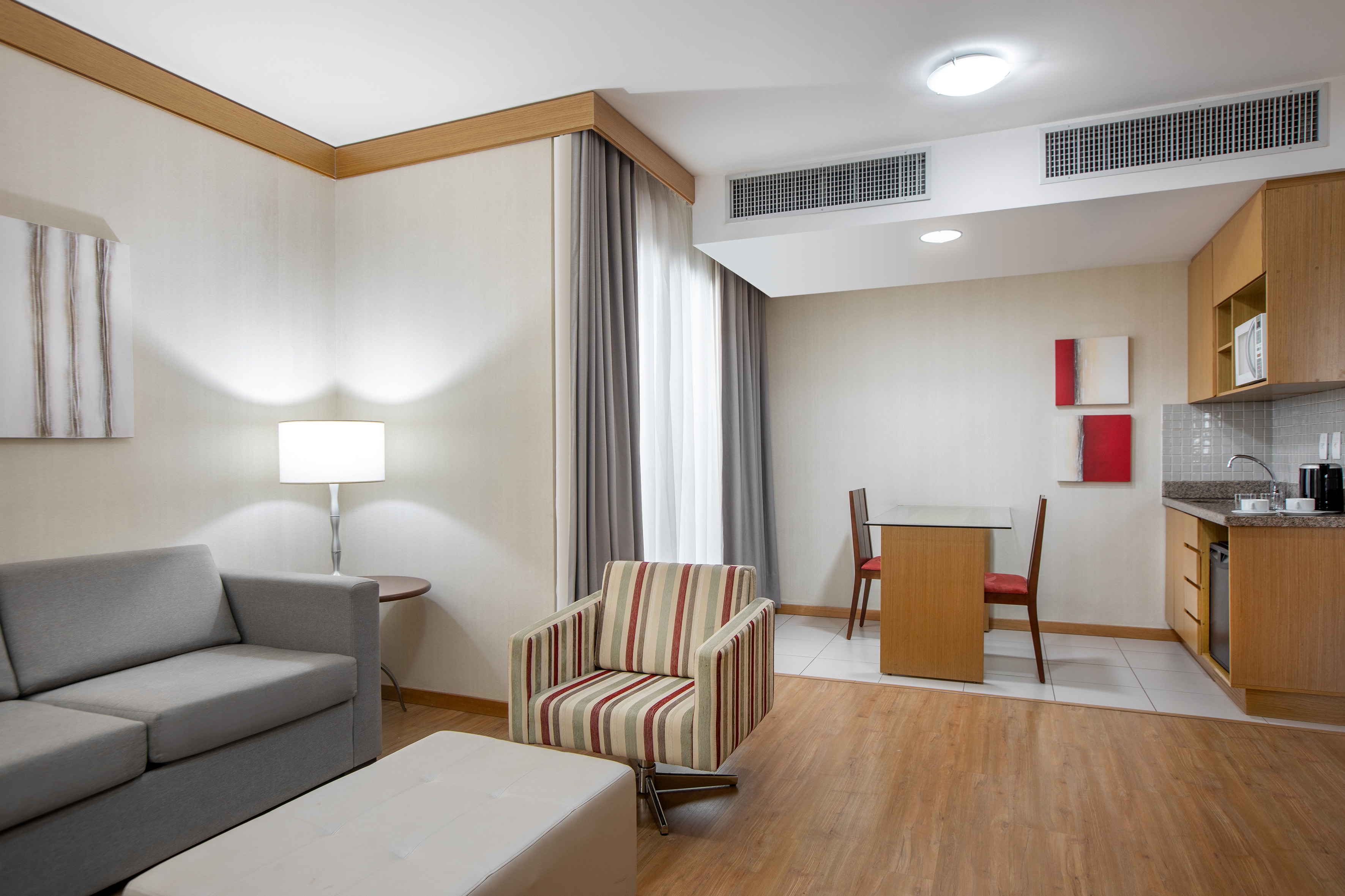 Modern hotel studio with living area, dining table, and integrated kitchenette.