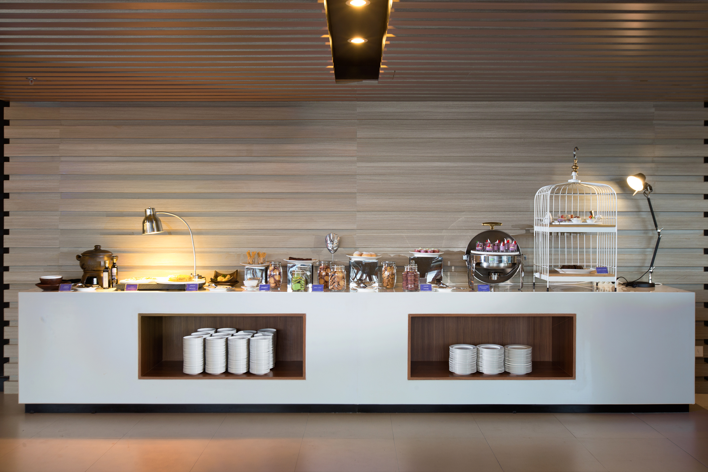 Hotel breakfast buffet featuring desserts, hot food, and white plates.