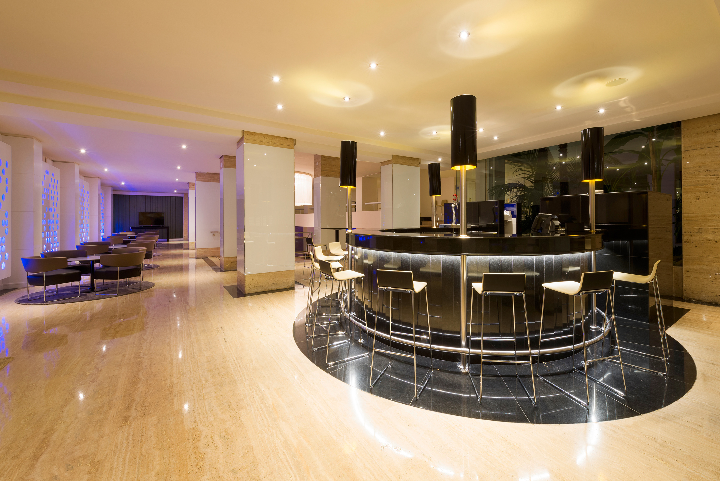 Elegant hotel bar and lounge with circular counter and modern seating.