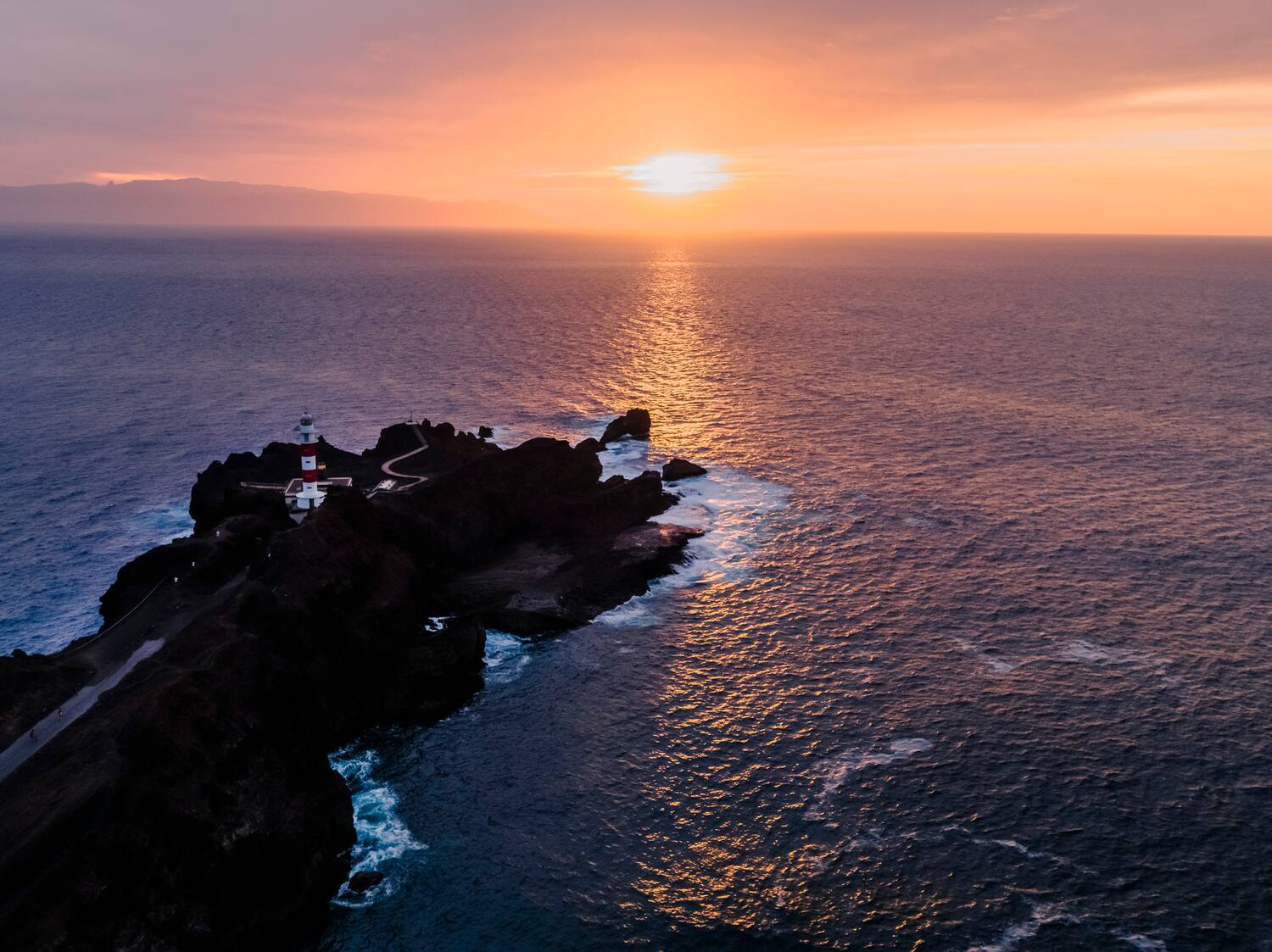 a lighthouse on a rocky island in the ocean