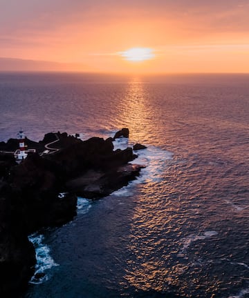 a lighthouse on a rocky island in the ocean
