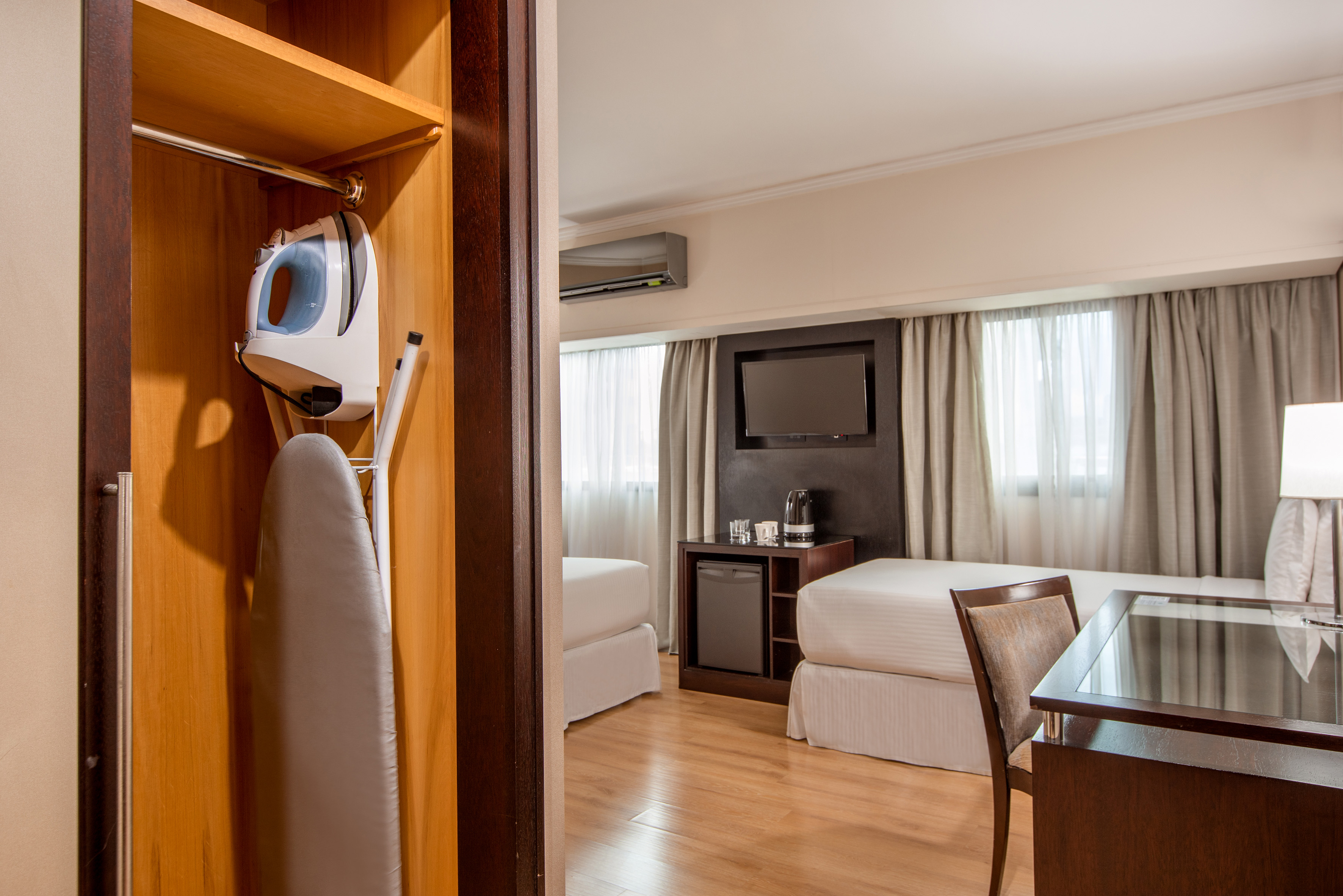 Hotel room with iron, ironing board, twin beds, TV, and minibar.