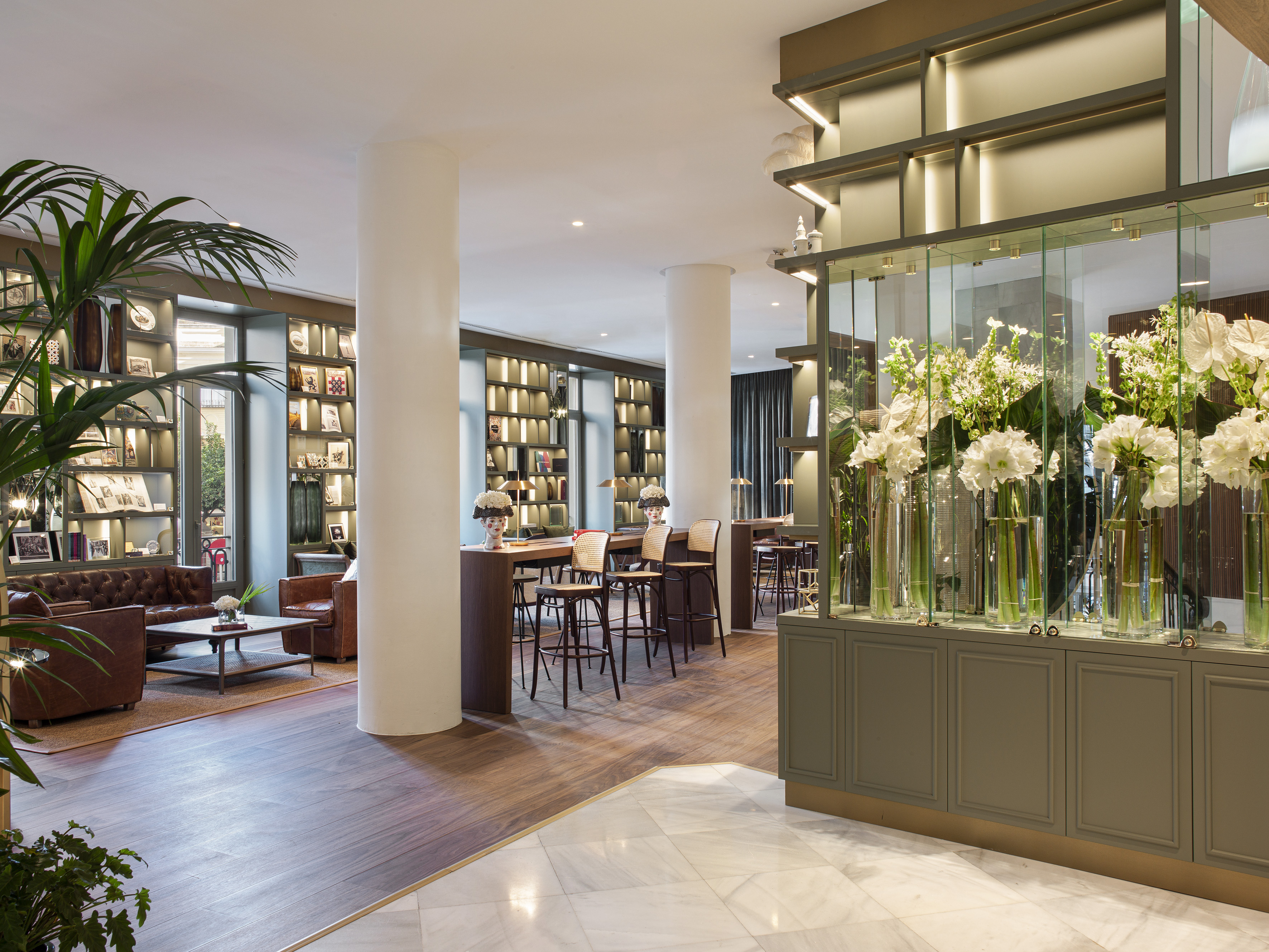 Elegant hotel lobby with leather seating, communal table, and white flowers.