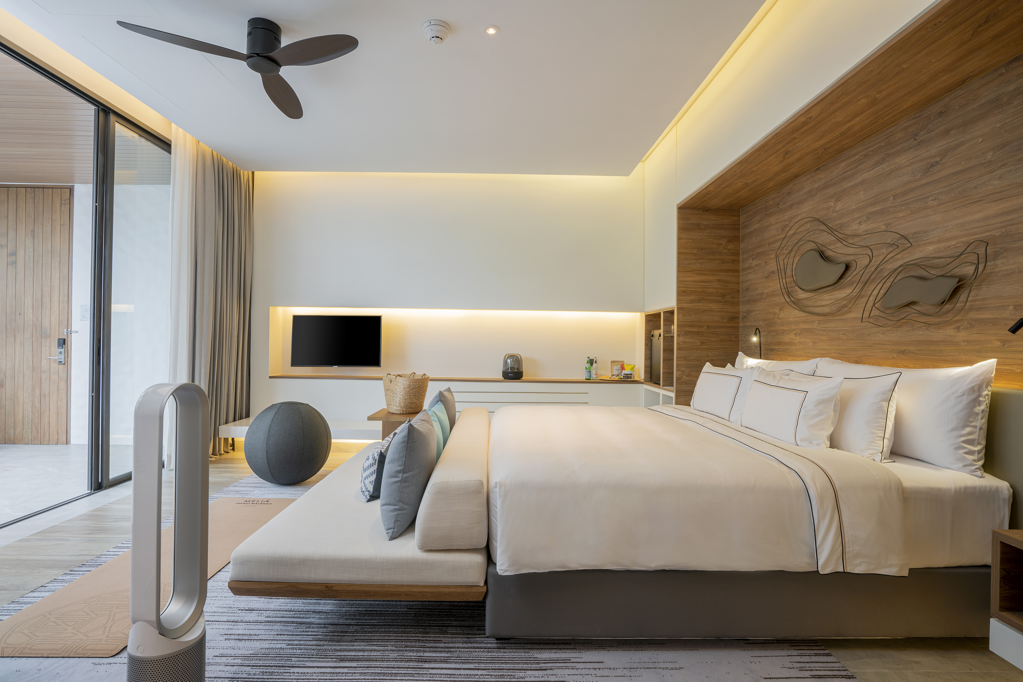 Luxury hotel bedroom with large bed, wooden wall, smart TV, and yoga mat.